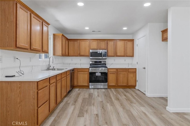 kitchen featuring light wood finished floors, a sink, appliances with stainless steel finishes, and visible vents