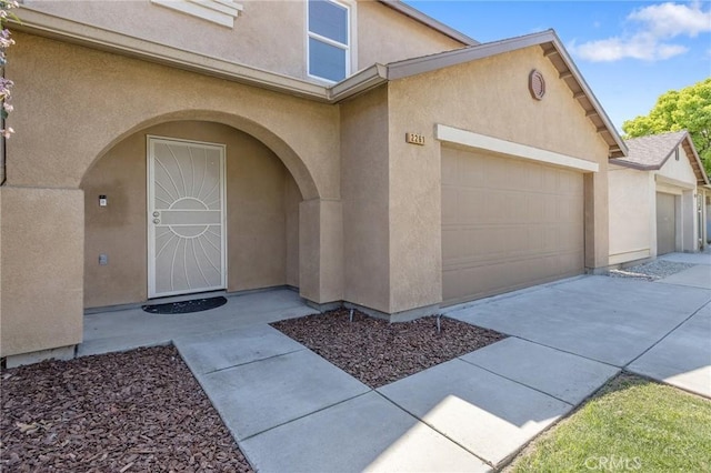doorway to property featuring stucco siding, concrete driveway, and a garage