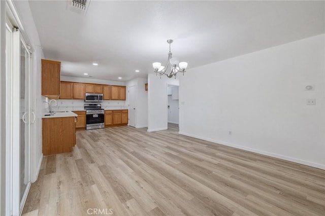 kitchen with recessed lighting, stainless steel appliances, light countertops, light wood finished floors, and a notable chandelier
