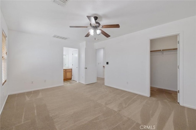 unfurnished bedroom featuring a walk in closet, visible vents, and light carpet