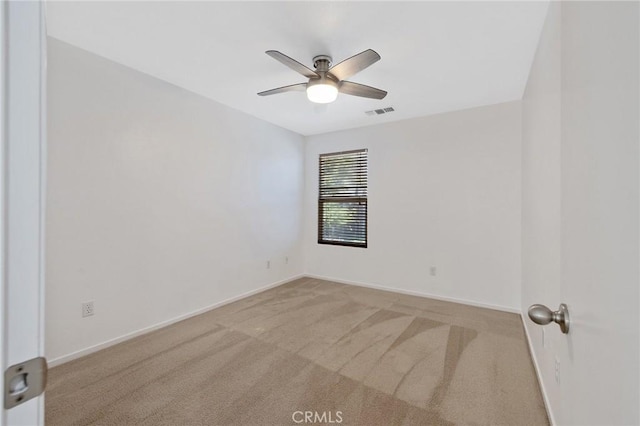 carpeted spare room with visible vents, a ceiling fan, and baseboards
