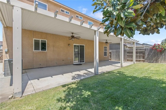 rear view of property with a patio area, a yard, ceiling fan, stucco siding, and fence