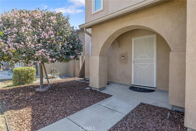 property entrance with stucco siding and fence