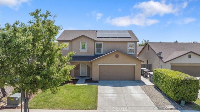 traditional home with stucco siding, solar panels, a front yard, concrete driveway, and an attached garage