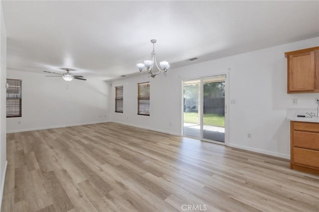 unfurnished living room featuring visible vents, baseboards, light wood-style flooring, and ceiling fan with notable chandelier