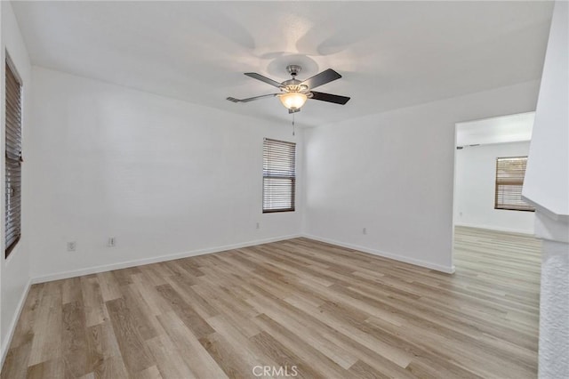empty room with a healthy amount of sunlight, baseboards, a ceiling fan, and light wood finished floors