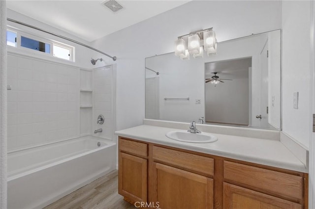 bathroom with wood finished floors, bathtub / shower combination, ceiling fan, vanity, and visible vents