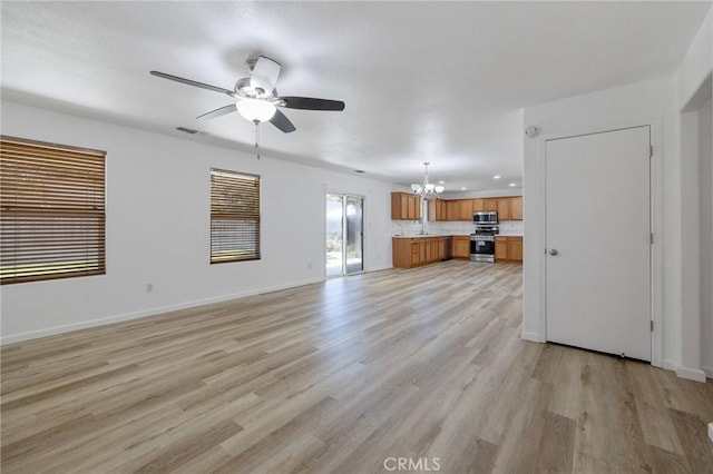 unfurnished living room with light wood-style flooring, visible vents, baseboards, recessed lighting, and ceiling fan with notable chandelier