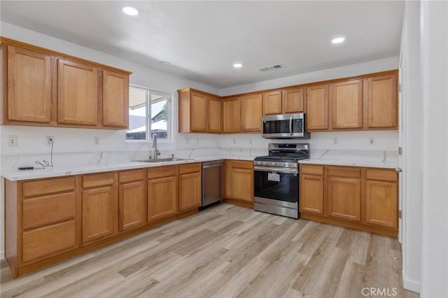 kitchen featuring a sink, visible vents, stainless steel appliances, light countertops, and light wood-type flooring