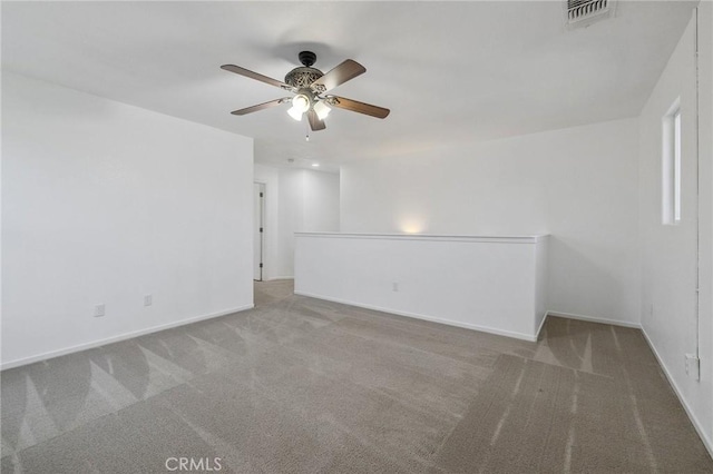 spare room featuring carpet, visible vents, ceiling fan, and baseboards