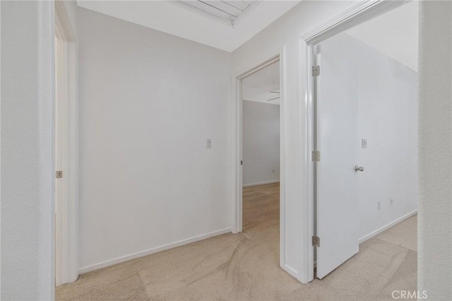 hallway with light colored carpet and baseboards