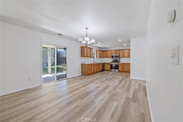 kitchen featuring appliances with stainless steel finishes, a chandelier, visible vents, light countertops, and light wood finished floors