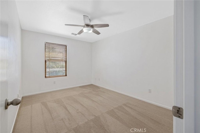 carpeted empty room with baseboards, visible vents, and a ceiling fan