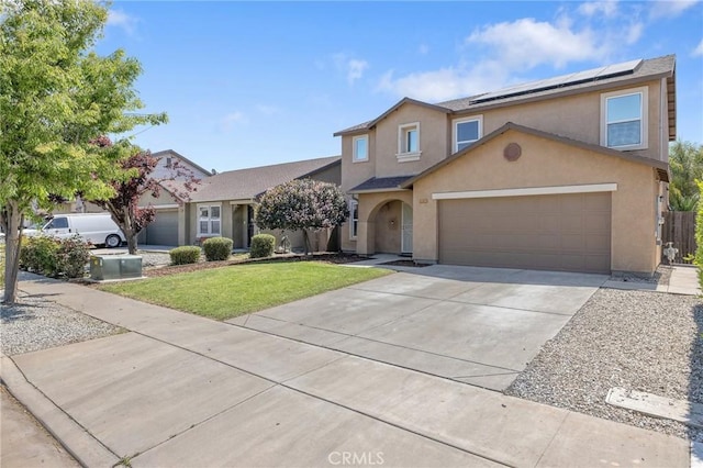 view of front of home with a front yard, an attached garage, driveway, roof mounted solar panels, and stucco siding