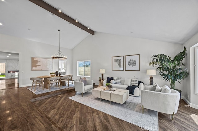 living area featuring baseboards, track lighting, wood finished floors, an inviting chandelier, and beam ceiling