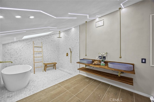 bathroom with recessed lighting, wood finished floors, a walk in shower, a freestanding bath, and vanity