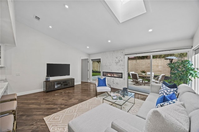 living room featuring lofted ceiling with skylight, recessed lighting, wood finished floors, and a fireplace