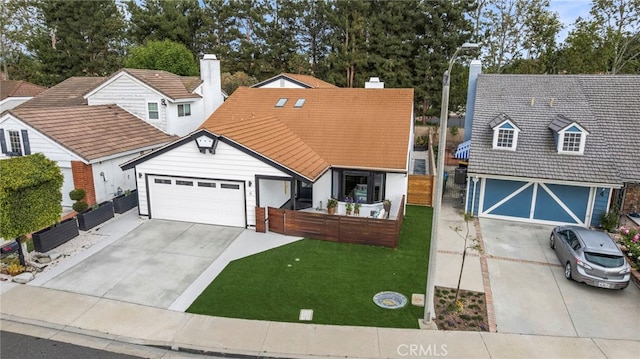 view of front facade featuring a chimney, fence, driveway, a front lawn, and an attached garage