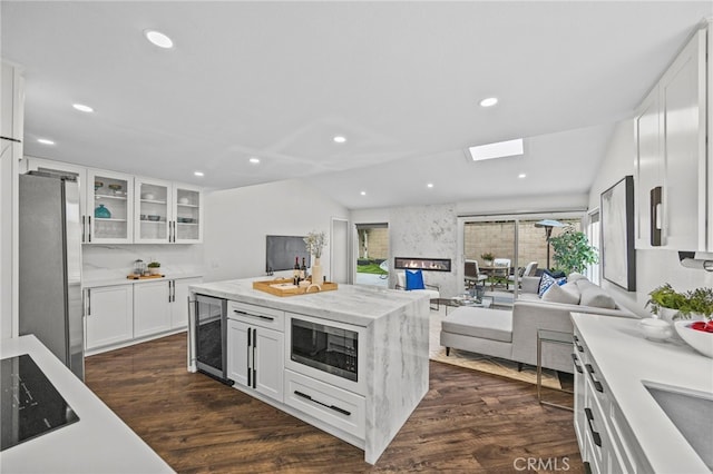 kitchen featuring freestanding refrigerator, built in microwave, open floor plan, dark wood-style flooring, and wine cooler