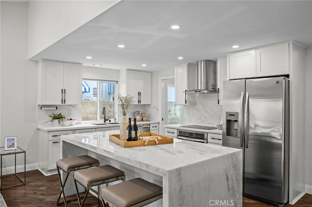 kitchen featuring a sink, stainless steel appliances, decorative backsplash, and wall chimney exhaust hood