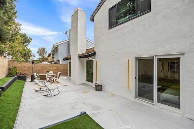 back of house with a patio, a chimney, stucco siding, and fence