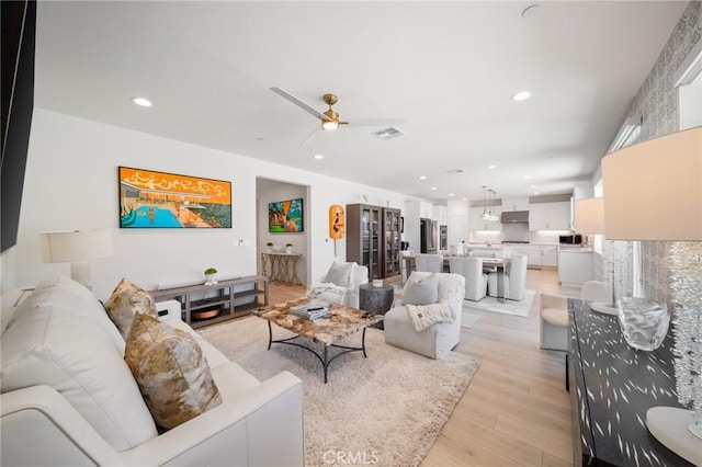 living room with a ceiling fan, recessed lighting, light wood finished floors, and visible vents