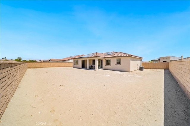 rear view of property with a patio, a fenced backyard, stucco siding, and solar panels