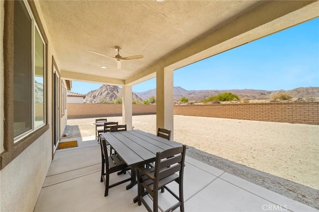 view of patio / terrace featuring ceiling fan, outdoor dining area, a mountain view, and a fenced backyard