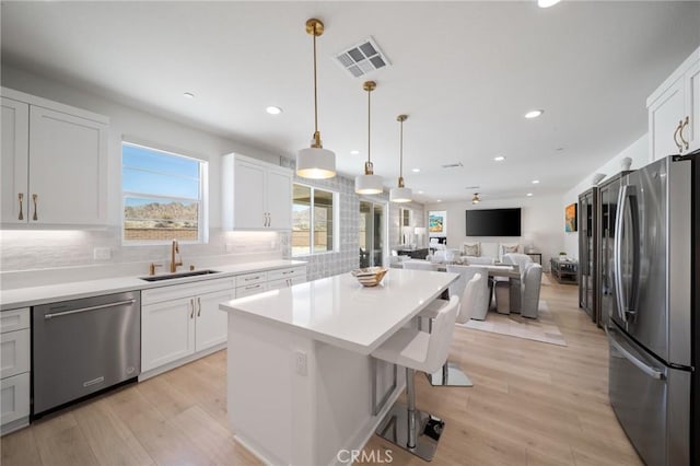 kitchen featuring appliances with stainless steel finishes, plenty of natural light, a sink, and visible vents