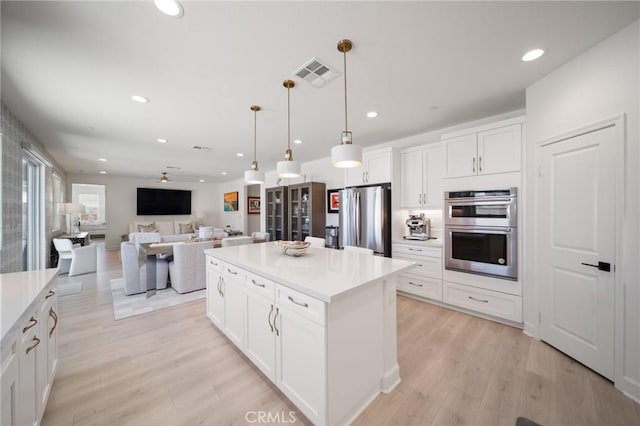 kitchen featuring visible vents, light wood-style flooring, appliances with stainless steel finishes, and white cabinets