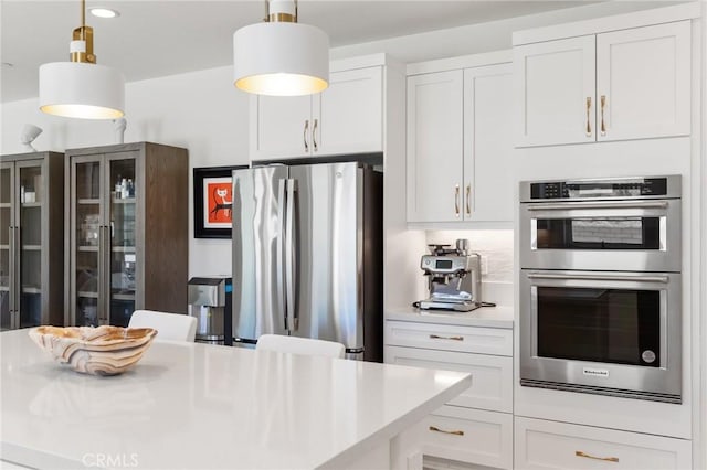kitchen with light countertops, white cabinets, stainless steel appliances, and decorative light fixtures