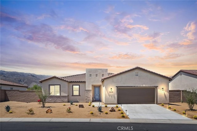view of front facade featuring a tiled roof, driveway, a garage, fence, and stucco siding