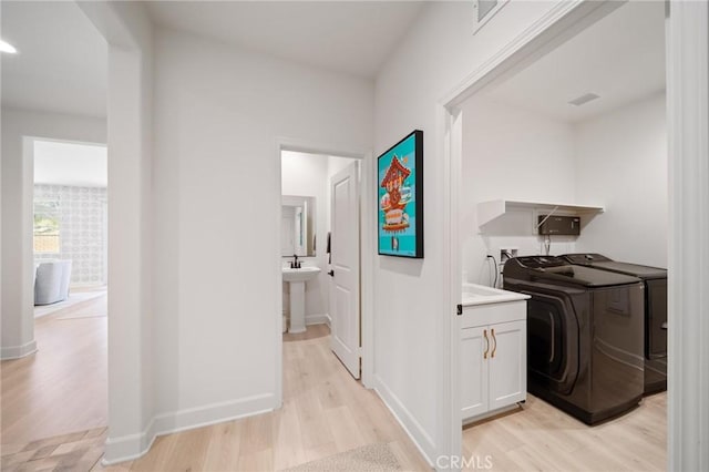 hall featuring baseboards, washer and clothes dryer, and light wood-style flooring