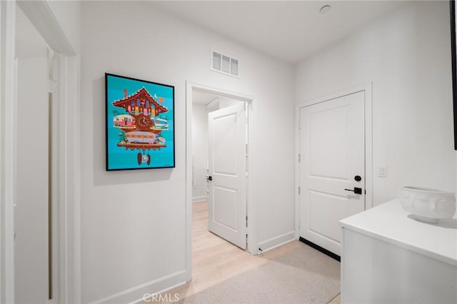 corridor with visible vents, light wood-style flooring, and baseboards