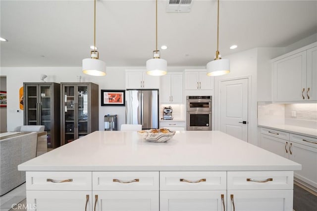 kitchen featuring visible vents, a center island, light countertops, white cabinets, and stainless steel appliances