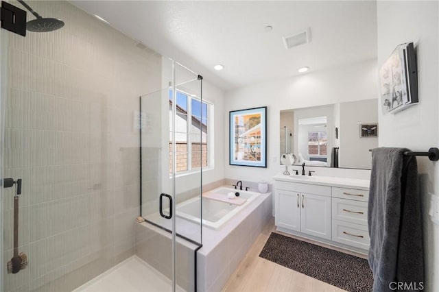 bathroom featuring vanity, wood finished floors, recessed lighting, a bath, and a stall shower