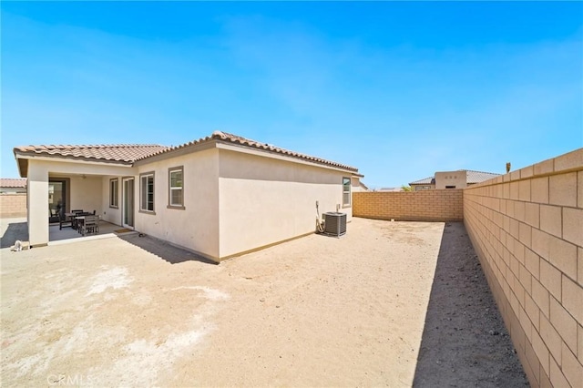 exterior space with cooling unit, a fenced backyard, a patio area, and stucco siding