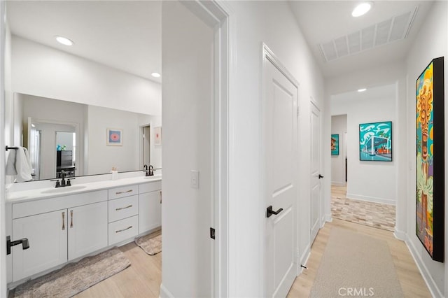 full bath with visible vents, double vanity, wood finished floors, recessed lighting, and a sink