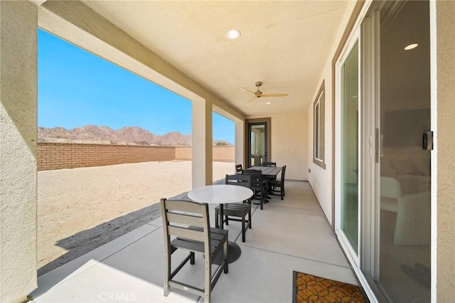 view of patio / terrace featuring ceiling fan, a mountain view, outdoor dining space, and a fenced backyard