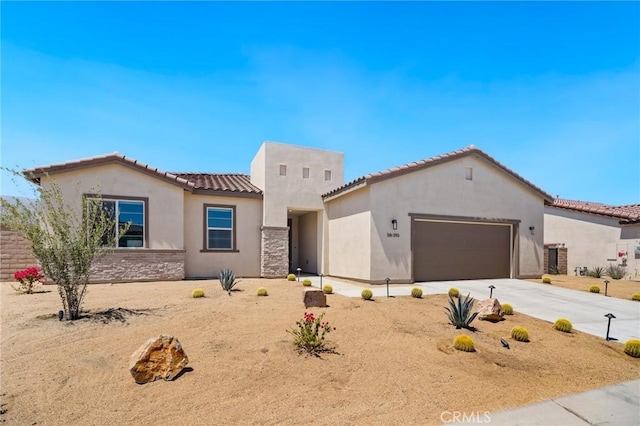 view of front of house featuring an attached garage, stucco siding, driveway, and a tiled roof