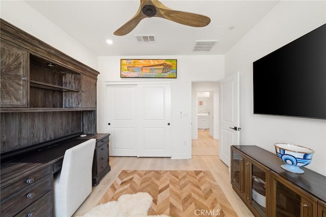 office area with visible vents, built in study area, ceiling fan, and light wood-type flooring