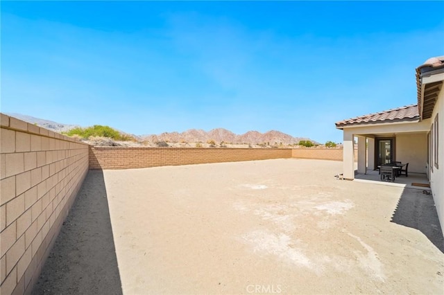 view of yard featuring a fenced backyard, a patio area, and a mountain view