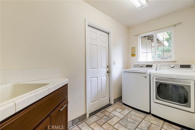 laundry room featuring baseboards, cabinet space, stone finish floor, and washing machine and dryer