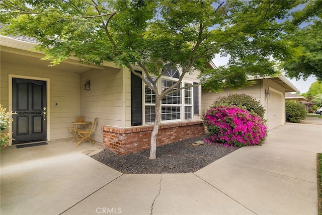 property entrance featuring driveway, a garage, and brick siding