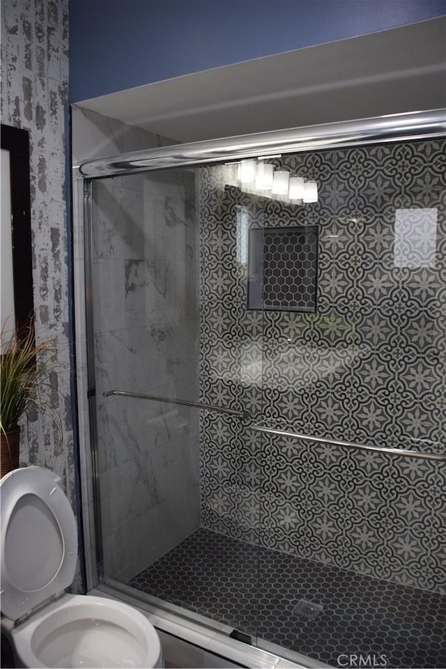 full bath featuring toilet, a stall shower, and wallpapered walls