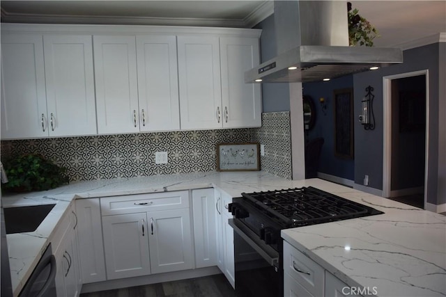 kitchen with gas stove, crown molding, white cabinets, and wall chimney range hood