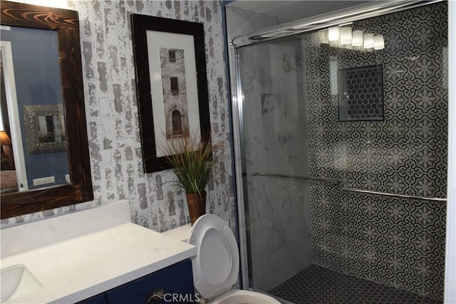 bathroom featuring wallpapered walls, a stall shower, toilet, and vanity