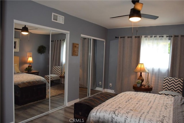 bedroom featuring visible vents, wood finished floors, a ceiling fan, and two closets