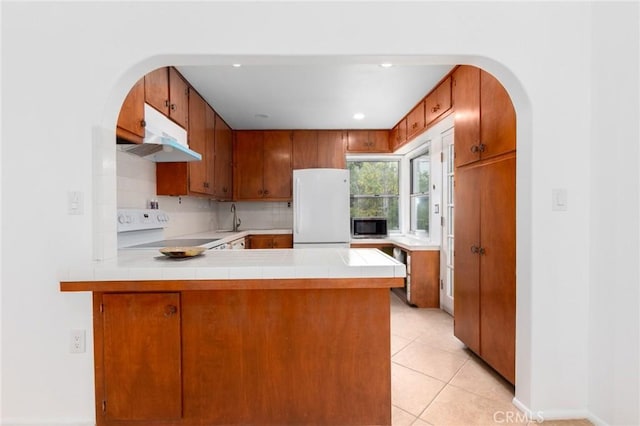 20095 Gustin Rd, Perris, CA 92570 - kitchen featuring brown cabinets, white appliances, arched walkways, a peninsula, and under cabinet range hood