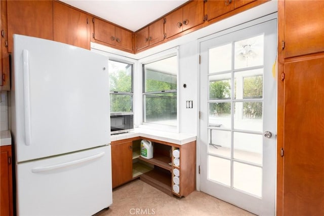 20095 Gustin Rd, Perris, CA 92570 - interior space featuring brown cabinetry, freestanding refrigerator, light countertops, stainless steel microwave, and light tile patterned floors